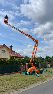 Podnośnik koszowy z wysięgnikiem wysuniętym ukośnie nad ulicę, operator w koszu