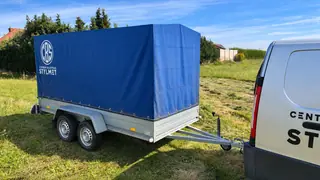 Przyczepa lekka 750 kg zaczepiona za samochodem dostawczym, widok z boku od strony zaczepu